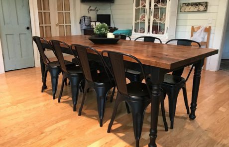 Custom wood dining table surrounded by black metal chairs