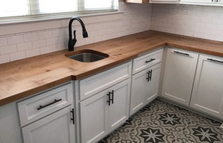 Bright white kitchen sink with black accents and custom butcher block countertop