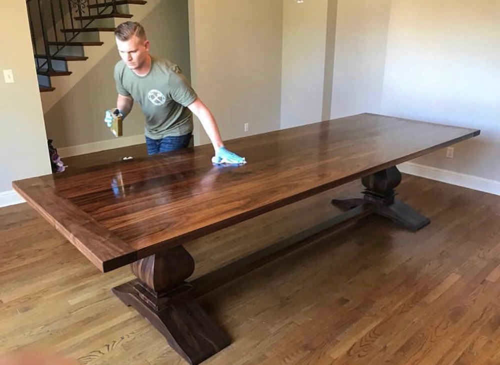 Randy applying finish to a dark wood dining table